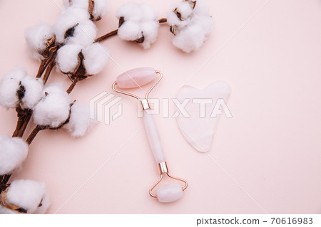 Pink roller face massager and gouache scraper on pink background. Anti age, lifting and toning treatment concept Pink roller face massager and gouache scraper on pink background. Anti age, lifting and toning treatment concept 70616983