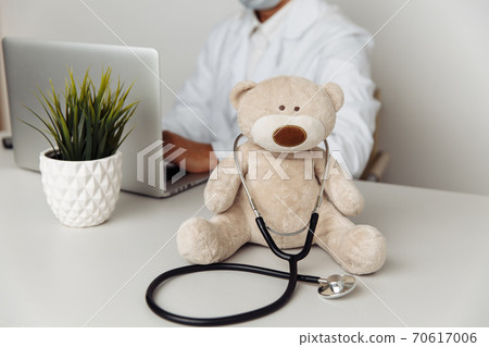 Teddy Bear with stethoscope and pediatrician working in laptop. Child healtcare concept 70617006