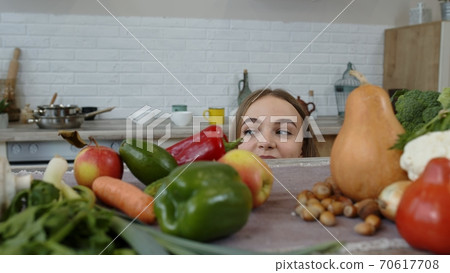 Girl peeping from under the table for vegetable and fruits. Weight loss, diet concept Girl peeping from under the table for vegetable and fruits. Weight loss, diet concept 70617708