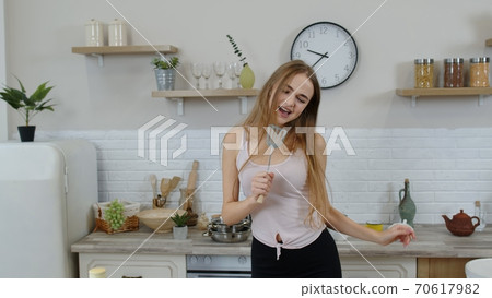 Happy vegan girl with slim waist dancing, singing in kitchen. Raw vegetable nutrition diet concept 70617982