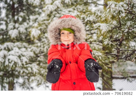 Happy boy plays with snow. Cute kid throwing snow in a winter park. Happy winter holidays. Winter fashion Happy boy plays with snow. Cute kid throwing snow in a winter park. Happy winter holidays. Winter fashion 70619082