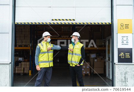 Workers with face mask greeting in front of warehouse, coronavirus concept. Workers with face mask greeting in front of warehouse, coronavirus concept. 70619544