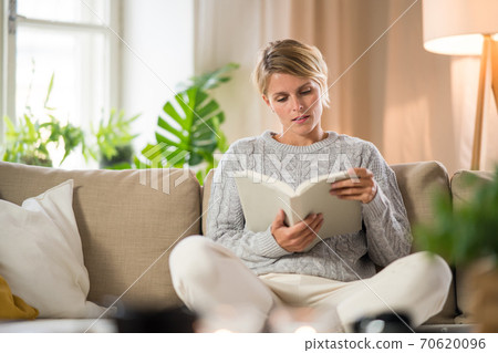 Portrait of woman relaxing with book indoors at home, mental health care concept. Portrait of woman relaxing with book indoors at home, mental health care concept. 70620096