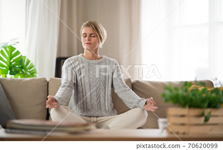 Portrait of woman indoors at home doing yoga, mental health and meditation concept. Portrait of woman indoors at home doing yoga, mental health and meditation concept. 70620099