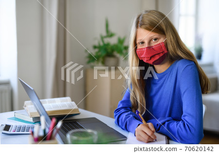 Schoolgirl learning online indoors at home, coronavirus concept. Schoolgirl learning online indoors at home, coronavirus concept. 70620142