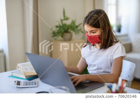 Schoolgirl learning online indoors at home, coronavirus concept. Schoolgirl learning online indoors at home, coronavirus concept. 70620146