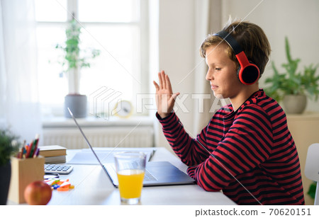 Schoolboy having online lesoon indoors at home, coronavirus concept. Schoolboy having online lesoon indoors at home, coronavirus concept. 70620151