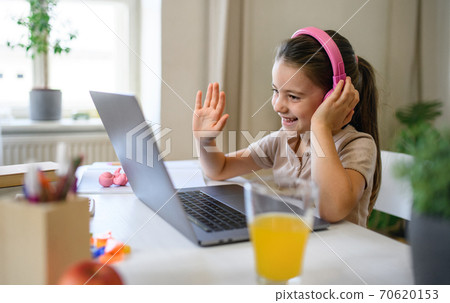 Schoolgirl having online lesoon indoors at home, coronavirus concept. Schoolgirl having online lesoon indoors at home, coronavirus concept. 70620153