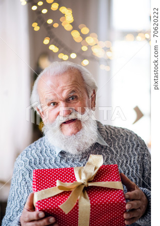 Front view of happy senior man with present box indoors at home at Christmas. 70620222
