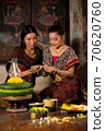 Two thai woman in traditional dress costume making and decorating Krathong. Loy Krathong Festival. 70620760