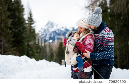 Father and mother with small child in winter nature, standing in the snow. 70620800