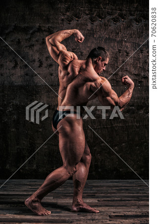 Sporty and healthy muscular man on dark grunge background Sporty and healthy muscular man on dark grunge background 70620838