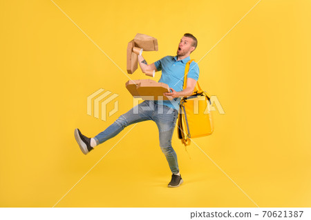 Delivery guy in blue uniform slipped and lost his balance and threw boxes of food from restaurant in direction. Clumsy food delivery guy broke up an order for customer. Poor product delivery 70621387