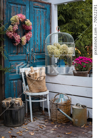 Autumn garden decoration set near the house, hydrangea wreath, old instruments, colorful flowers potted Autumn garden decoration set near the house, hydrangea wreath, old instruments, colorful flowers potted 70622291