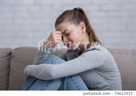 Lonely millennial woman feeling hopeless or desperate, crying on sofa at home 70623015