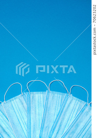 Stack of Disposable blue medical face masks on blue background 70623202