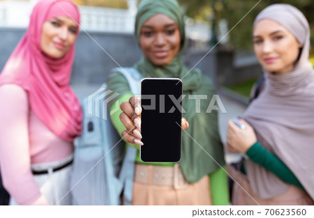 Three Muslim Women Showing Smartphone Screen Outdoors, Focus On Phone 70623560