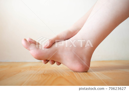 Young female suffering from foot pain or numbness at home. Causes of pain include plantar fasciitis, gout, arthritis, tendinitis, diabetic neuropathy or overuse injuries. Healthcare concept. 70623627