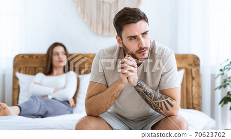 Man and woman feeling stressed and angry at each other, sits on wooden bed and look to side of free space 70623702