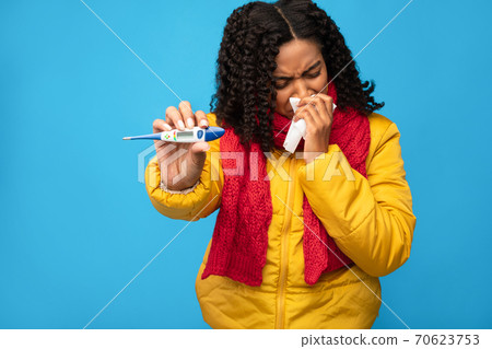 Sick African Woman Showing Thermometer Sneezing In Tissue, Blue Background 70623753