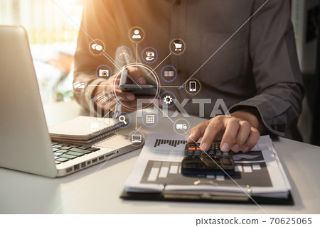 businessman calculates financials with graph paper on the laptop computer, cell phone on the cost of home office. businessman calculates financials with graph paper on the laptop computer, cell phone on the cost of home office. 70625065