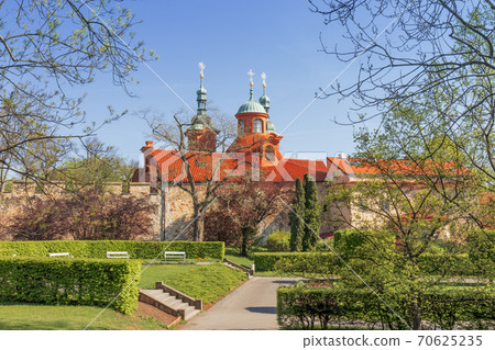 Petrin gardens with St. Lawrence Church on Petrin hill and surrounding area, the wall, buildings and beautiful park, garden. Prague, Czech Republic, spring, bright sunny day, shortly after sunrise 70625235