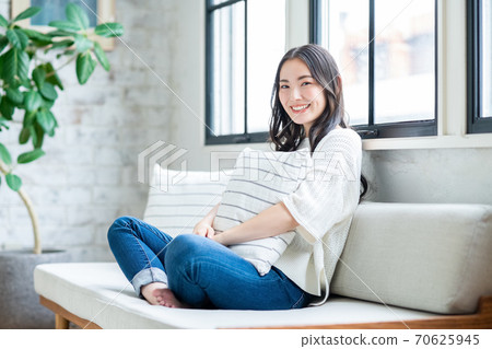 A young woman holding a cushion and relaxing in the living room 70625945