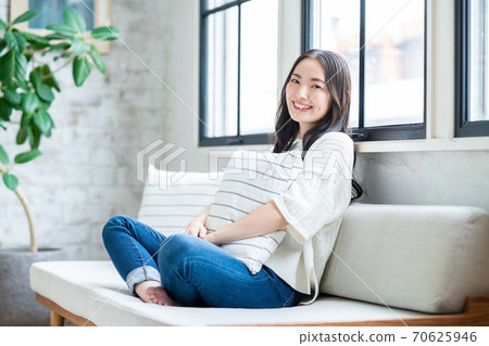 A young woman holding a cushion and relaxing in the living room A young woman holding a cushion and relaxing in the living room 70625946