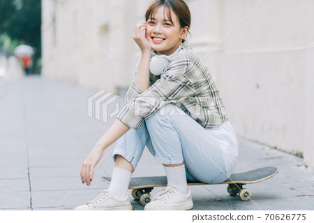 Girl learning to skateboard on the street, street activities 70626775