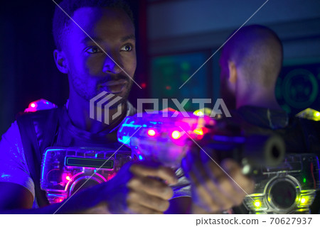 playing laser tag with friends on dark labyrinth in colorful lights 70627937