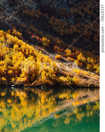 Mountain lake with transparent water and colorful autumnal trees. Mountains and lake Mountain lake with transparent water and colorful autumnal trees. Mountains and lake 70628337