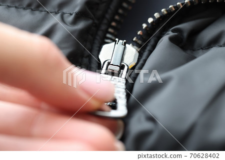 Hand fastens the zipper on jacket closeup Hand fastens the zipper on jacket closeup 70628402