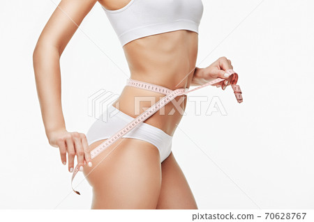 Slim tanned woman's body isolated on white background - waist measurement 70628767