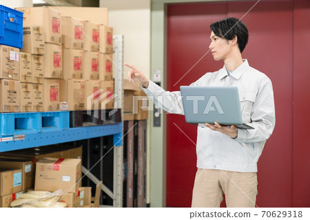 A man in work clothes who manages inventory in a warehouse 70629318