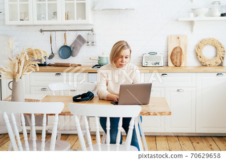 woman working on laptop in the kitchen woman working on laptop in the kitchen 70629658