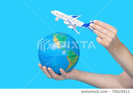 Travel concept. Female hands holding globe and figurine of passenger plane on blue background 70629812