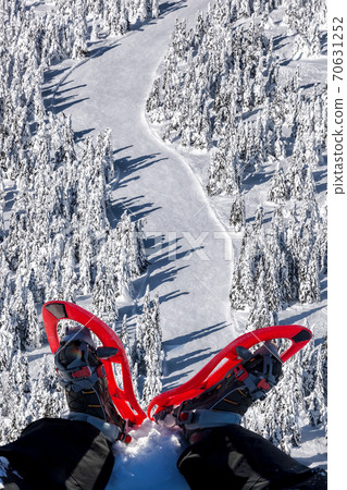 Snowshoes against winter forest with ski slope 70631252