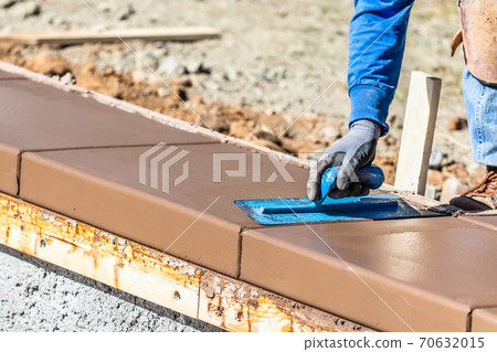 Construction Worker Using Trowel On Wet Cement Forming Coping Around New Pool Construction Worker Using Trowel On Wet Cement Forming Coping Around New Pool 70632015