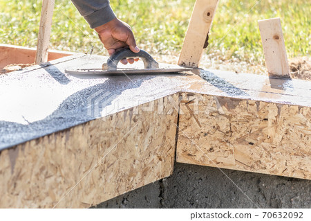 Construction Worker Using Wood Trowel On Wet Cement Forming Coping Around New Pool Construction Worker Using Wood Trowel On Wet Cement Forming Coping Around New Pool 70632092