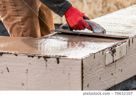 Construction Worker Using Wood Trowel On Wet Cement Forming Coping Around New Pool 70632107