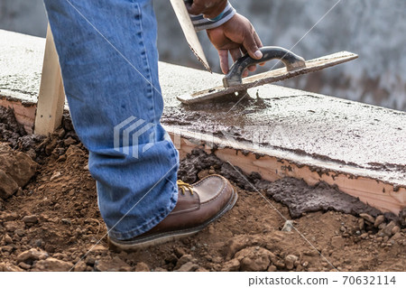 Construction Worker Using Wood Trowel On Wet Cement Forming Coping Around New Pool 70632114