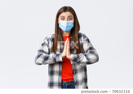 Different emotions, covid-19 pandemic, coronavirus self-quarantine and social distancing concept. Hopeful enthusisatic girl, volunteer in medical mask, asking please, begging help, hold hands in pray 70632158