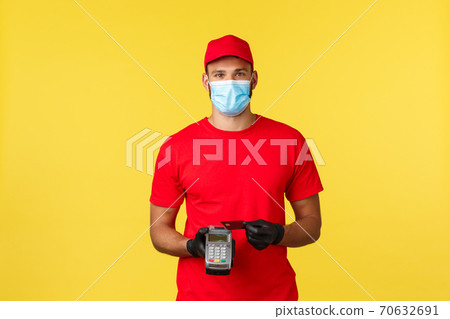 Food delivery, tracking orders, covid-19 and self-quarantine concept. Friendly courier in red uniform, medical mask and gloves, using credit card on POS terminal to pay for order contactless Food delivery, tracking orders, covid-19 and self-quarantine concept. Friendly courier in red uniform, medical mask and gloves, using credit card on POS terminal to pay for order contactless 70632691