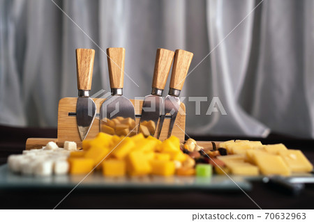 Cheese dish with various cheeses and dried fruits on a sliced Board with devices for slicing.Special Board for slicing cheese with cheese and dried fruits Cheese dish with various cheeses and dried fruits on a sliced Board with devices for slicing.Special Board for slicing cheese with cheese and dried fruits 70632963