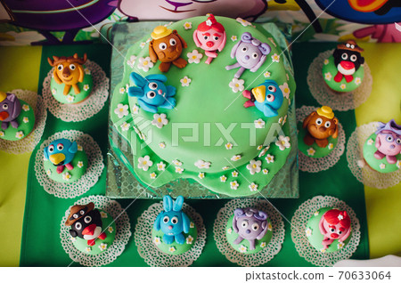 festive children's table with a beautiful cake decorated with green and multi-colored biscuits. candy. Children's birthday.Cake for children's birthday in cartoon style festive children's table with a beautiful cake decorated with green and multi-colored biscuits. candy. Children's birthday.Cake for children's birthday in cartoon style 70633064