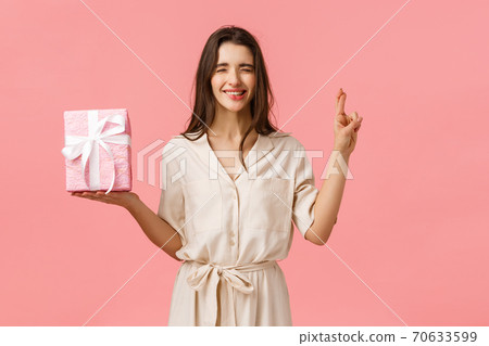 Anticipation, celebrating and presents concept. Cute b-day girl in lovely dress making wish, hope find exactly what she wished for inside gift box, cross fingers and close eyes, biting lip tempting Anticipation, celebrating and presents concept. Cute b-day girl in lovely dress making wish, hope find exactly what she wished for inside gift box, cross fingers and close eyes, biting lip tempting 70633599