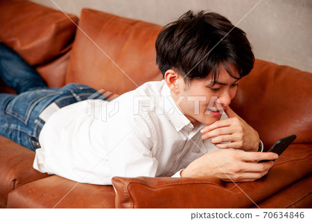 A man looking at a smartphone in the room A man looking at a smartphone in the room 70634846
