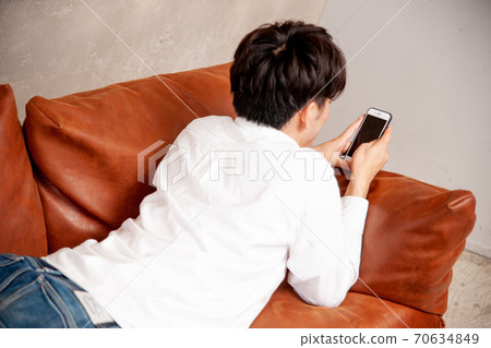 A man looking at a smartphone in the room A man looking at a smartphone in the room 70634849