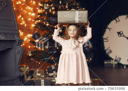 Little girl in a cute dress near christmas tree with present Little girl in a cute dress near christmas tree with present 70635998