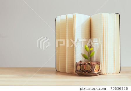 Coins in a bottle and the green tree with book background on the table, Financial planning. Coins in a bottle and the green tree with book background on the table, Financial planning. 70636326